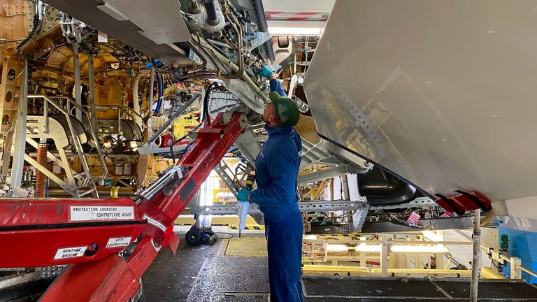 Ein Angesteller von Airbus mit Schutzhelm betrachtet das Gerüst eines Airbus-Flugzeugs in der Airbus-Werkhalle in Toulouse, Frankreich.