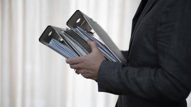 Aktenordner werden zum Schreibtisch getragen