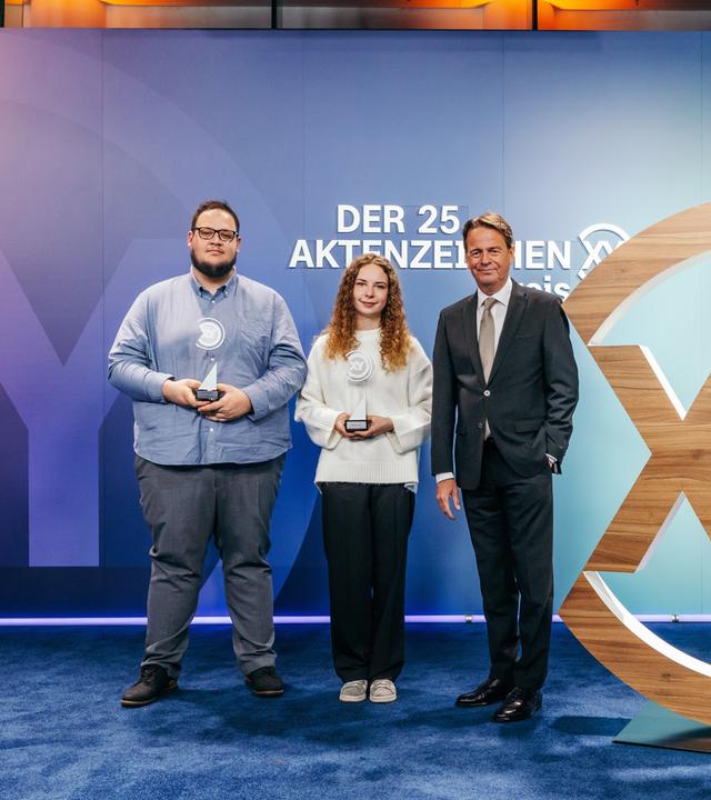 Das Bild zeigt Moderator Rudi Cerne mit zwei Preisträgern des Aktenzeichen XY-Preis.