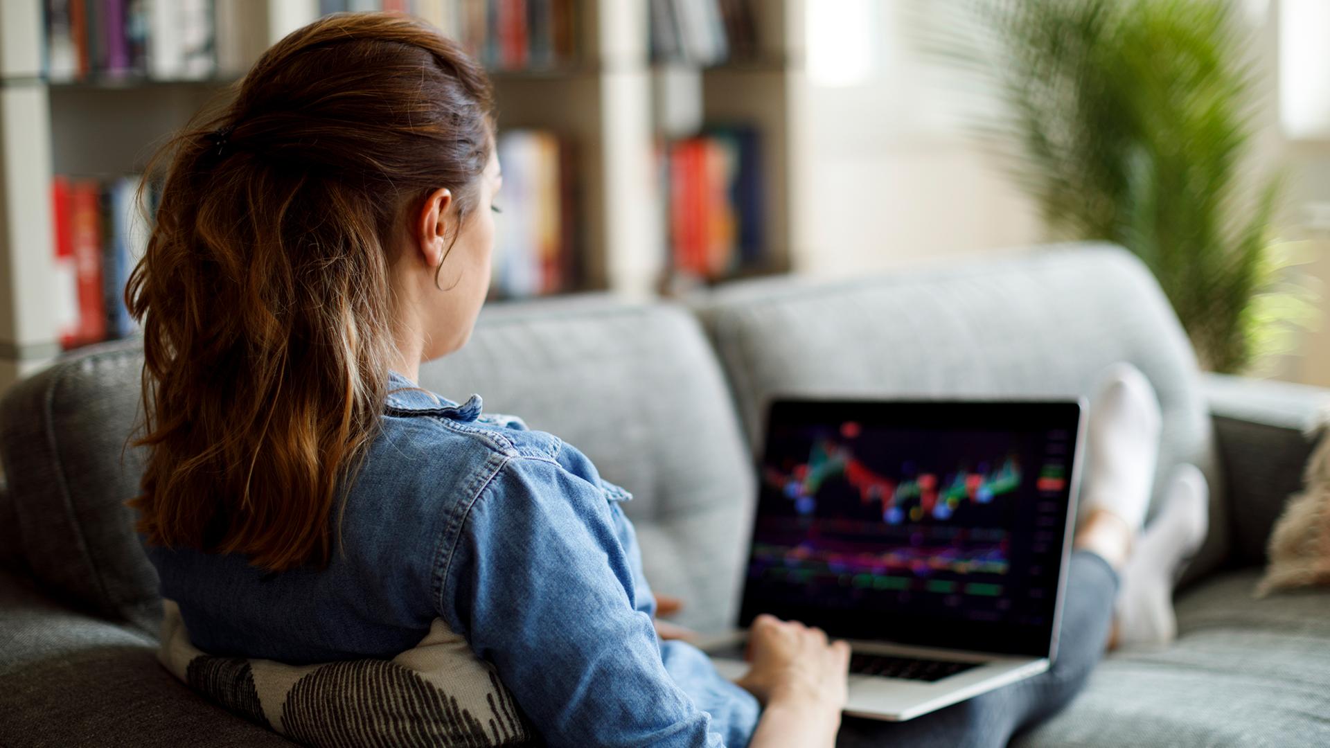 Ein Frau sitzt am Laptop und kauft Aktien.
