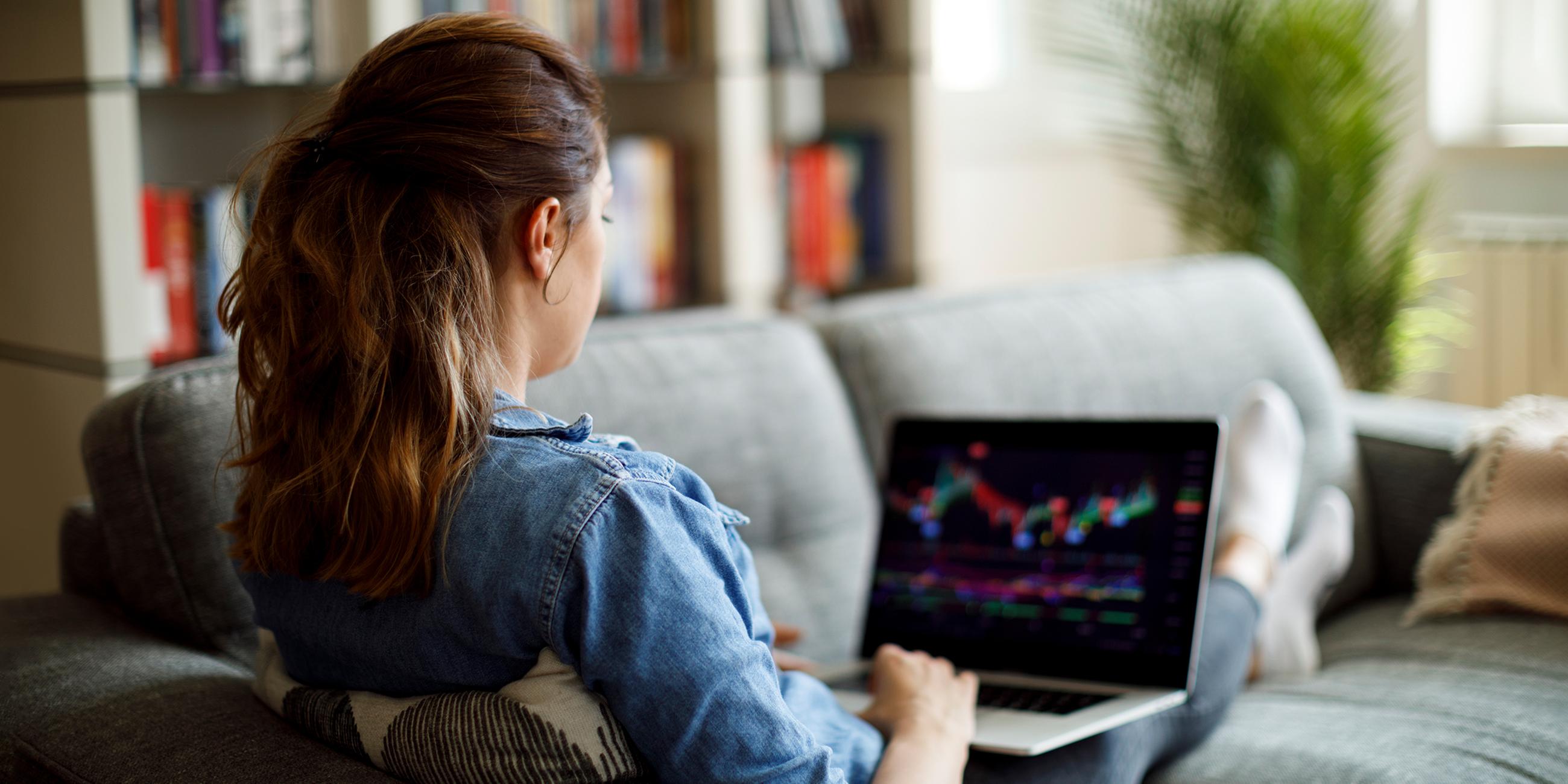 Ein Frau sitzt am Laptop und kauft Aktien.