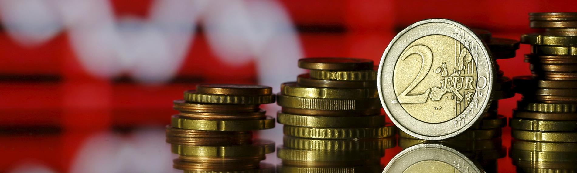 Euro- und Centmünzen vor einem Aktienkurs
