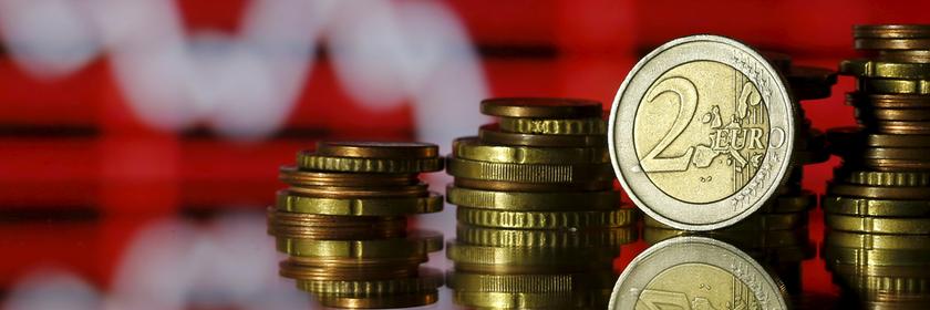 Euro- und Centmünzen vor einem Aktienkurs