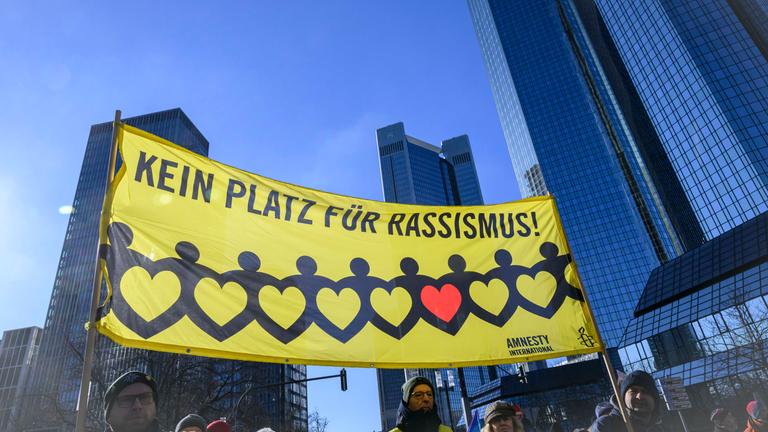  Kein Platz für Rassismus steht auf dem Plakat direkt vor den Türmen der Deutschen Bank bei einer Demonstration in Frankfurt.