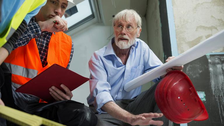 Architekt und zwei Bauarbeiter auf der Baustelle eines neuen Gebäudes