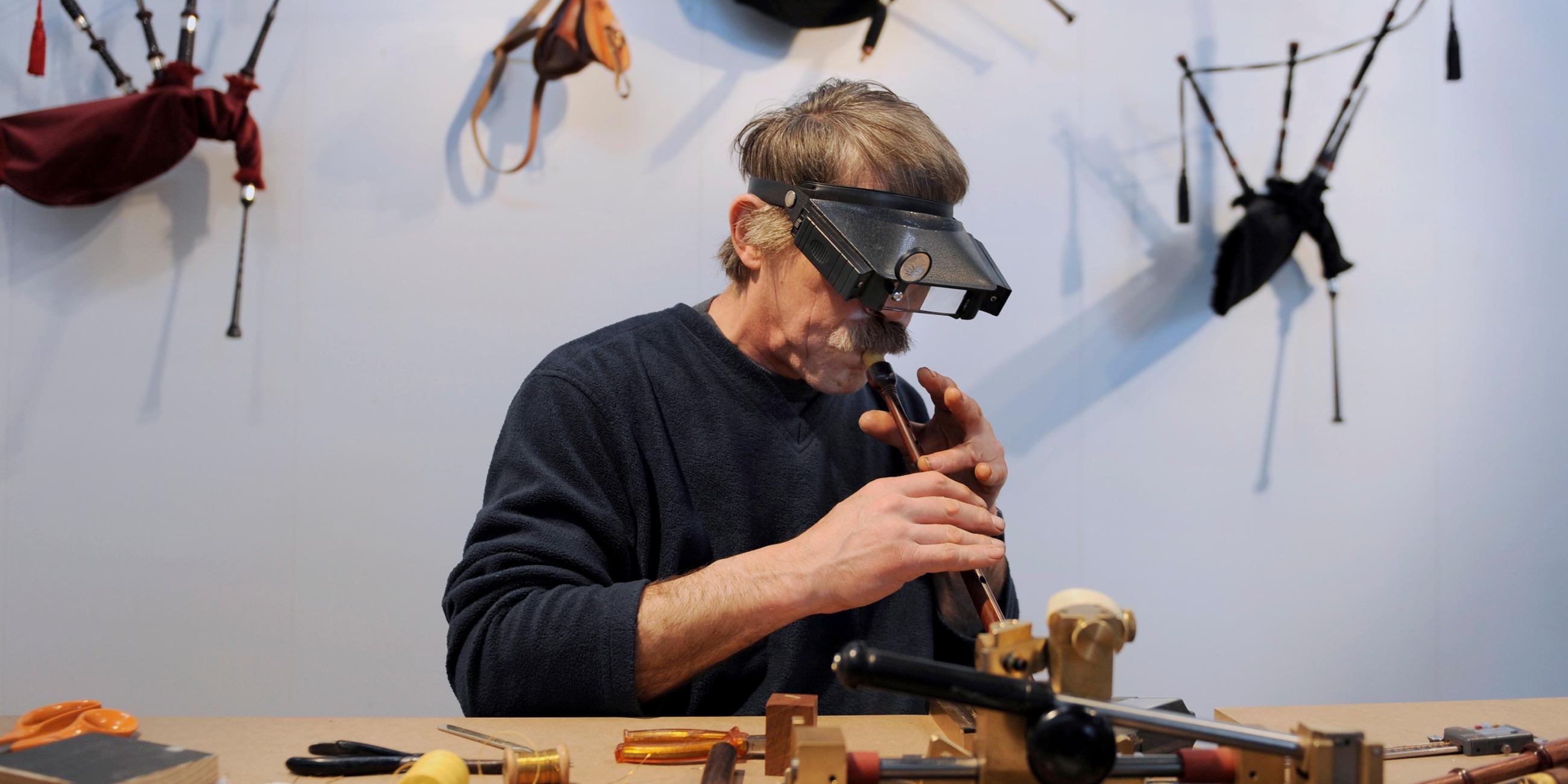 Eine älterer Herr geht seiner Tätigkeit als Instrumentbauer nach.