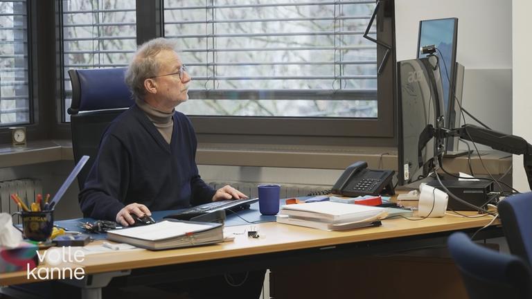 Alter Mann sitzt am Rechner im Büro