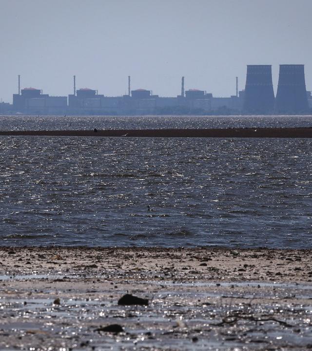 Ukraine, Energodar: Das Kernkraftwerk Saporischschja ist im Hintergrund des flachen Kachowka-Stausees nach der Zerstörung des Staudamms zu sehen.