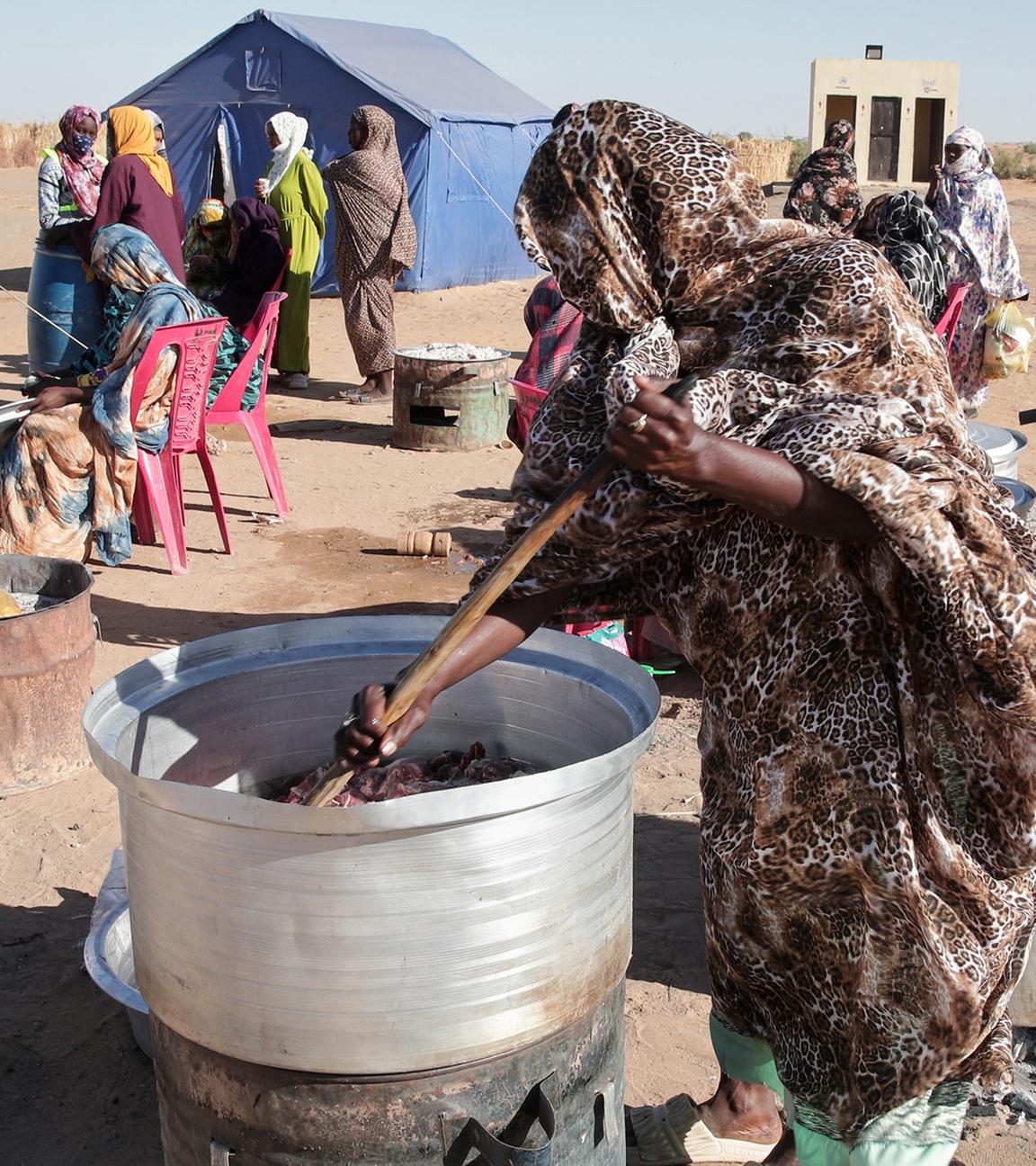  Sudanesische Frauen, die aus Al-Faschir vertrieben wurden, kochen gemeinsam im neu errichteten Lager El-Afadh in Al Dabbah im Nordsudan.