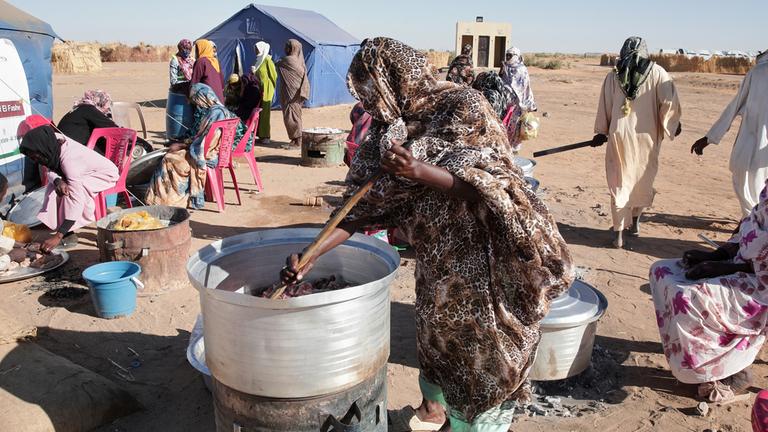  Sudanesische Frauen, die aus Al-Faschir vertrieben wurden, kochen gemeinsam im neu errichteten Lager El-Afadh in Al Dabbah im Nordsudan.