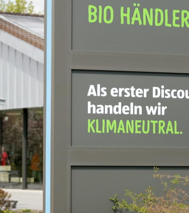 Schild vor ALDI Süd: "Als erster Discounter handeln wir klimaneutral"