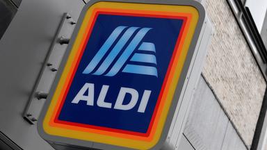 An einer Hausfassade ist ein Schild des Aldi-Logos angebracht.