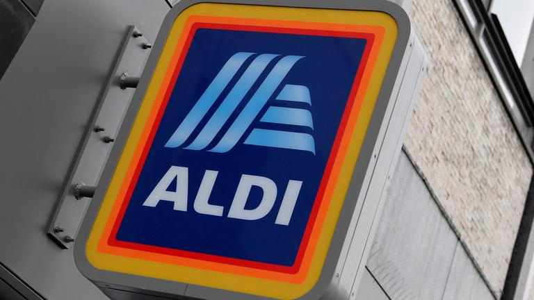 An einer Hausfassade ist ein Schild des Aldi-Logos angebracht.