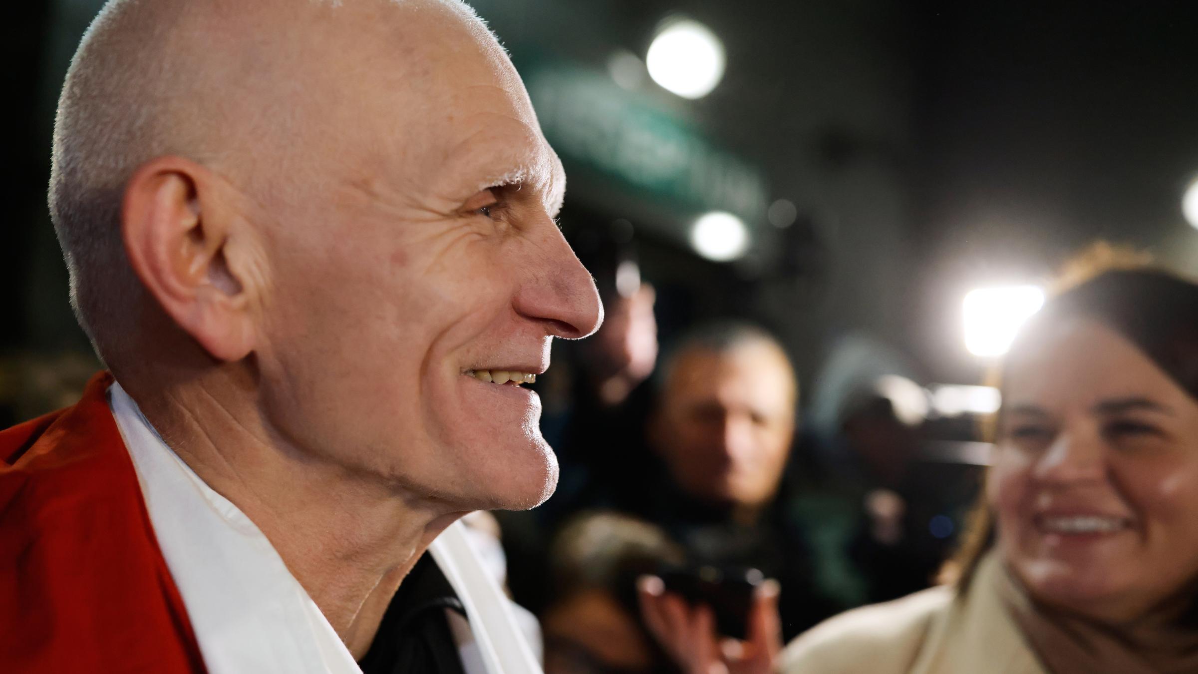 Der Friedensnobelpreisträger Ales Bjaljazki, einer der freigelassenen belarussischen Gefangenen, lächelt, als er am 13.12.2025, in der US-Botschaft in Vilnius, Litauen, eintrifft, während die belarussische Oppositionsführerin Sviatlana Tsikhanouskaya (im Hintergrund) daneben steht.