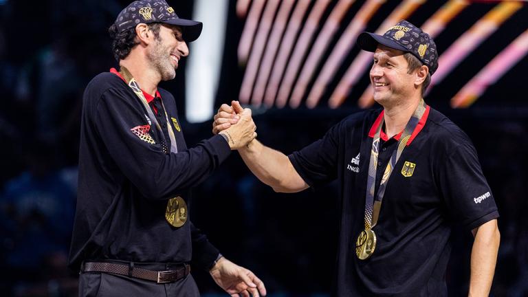 Alex Mumbru (Bundestrainer Deutschland) und Alan Ibrahimagic (Co-Trainer Deutschland) klatschen sich während des FIBA EuroBasket 2025, am 14.09.2025 in Riga, lachend ab.