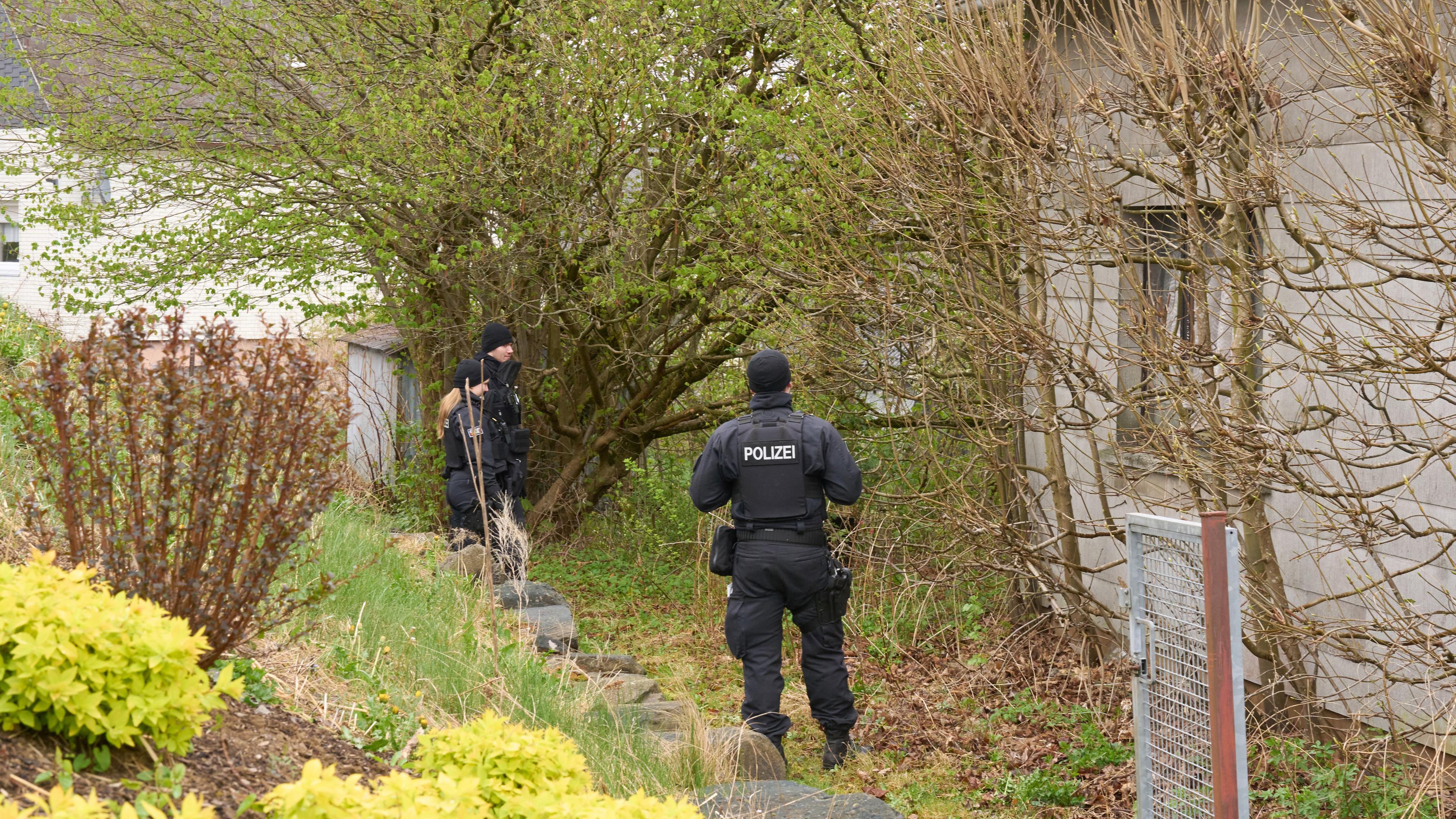 Zwei Polizisten stehen in Rahmen von Ermittlungsarbeiten an einem Haus.