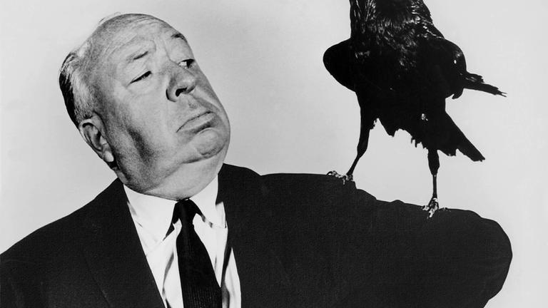 Alfred Hitchcock hat eine Krähe auf seiner Schulter.