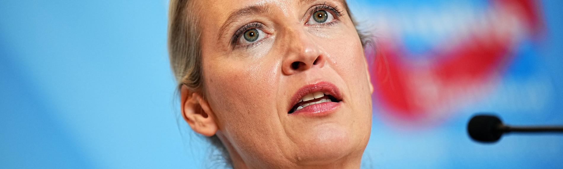 Alice Weidel, Co-Vorsitzende der AfD-Bundestagsfraktion vor einem AfD-Logo.