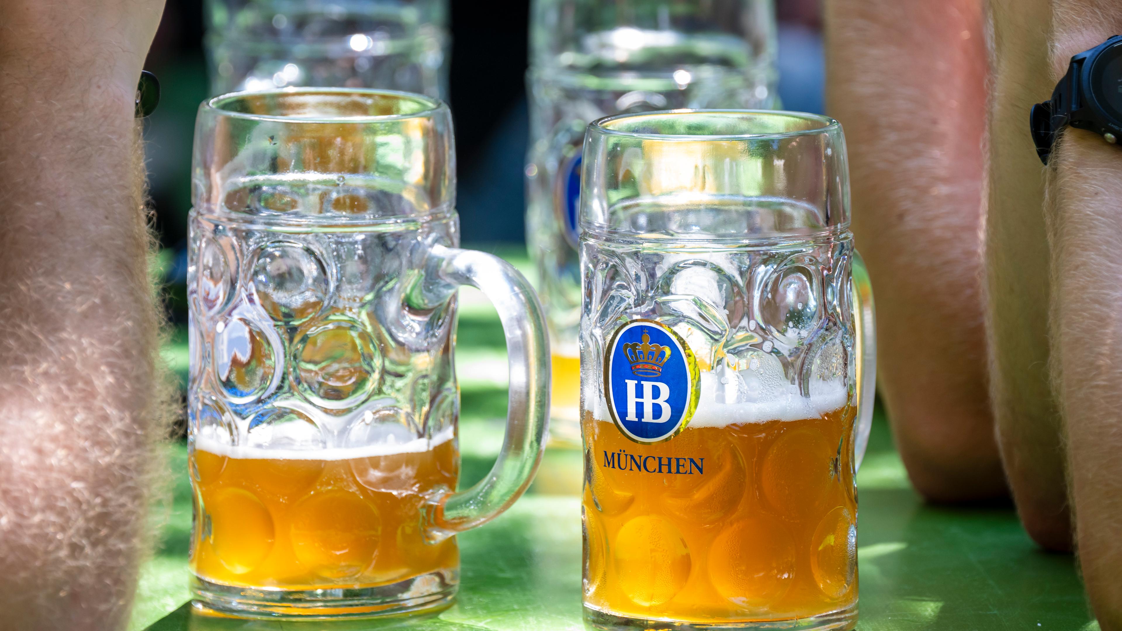 Bayern, München: Besucher eines Biergartens genießen um die Mittagszeit ihre Kühle Maß Bier.