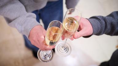 Zwei Teenager stoßen zuhause mit Sekt an.