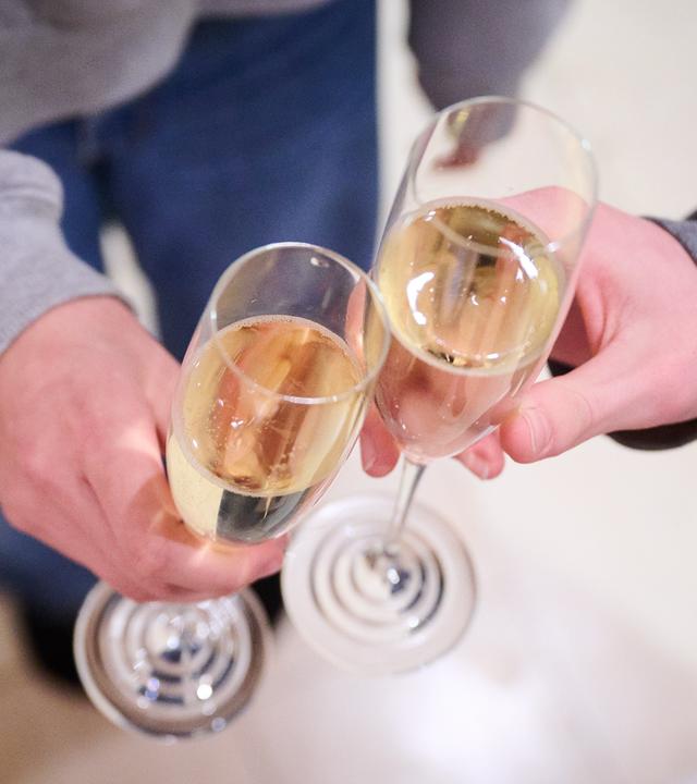 Zwei Teenager stoßen zuhause mit Sekt an.