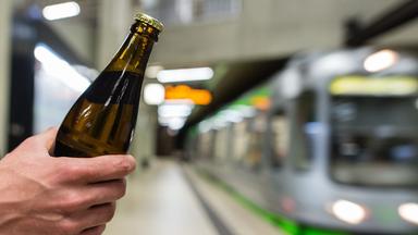 Ein Mann hält in Hannover (Niedersachsen) an einer Haltestelle der Hannoveraner Verkehrsbetriebe ÜSTRA ein Bier in der Hand.