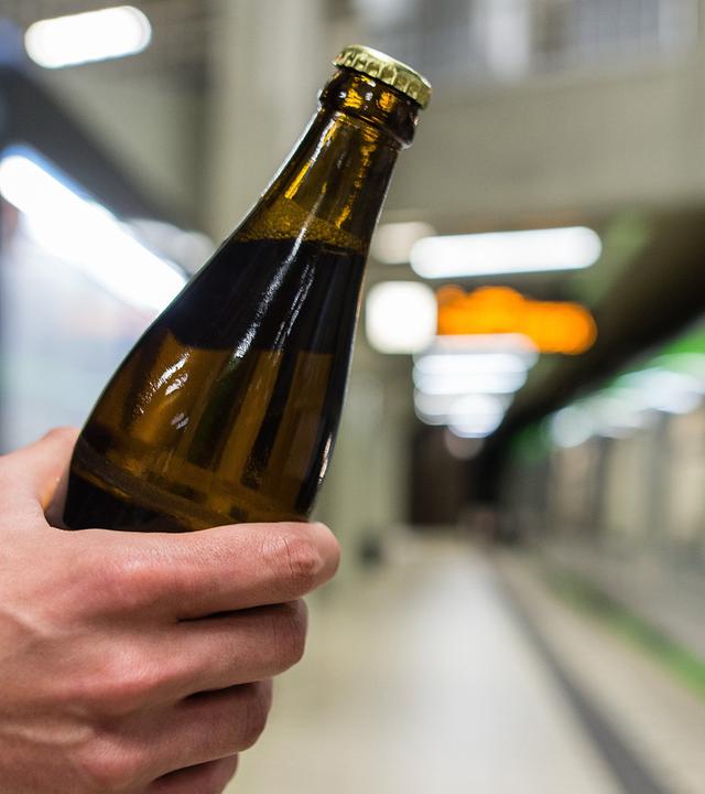 Ein Mann hält in Hannover (Niedersachsen) an einer Haltestelle der Hannoveraner Verkehrsbetriebe ÜSTRA ein Bier in der Hand.