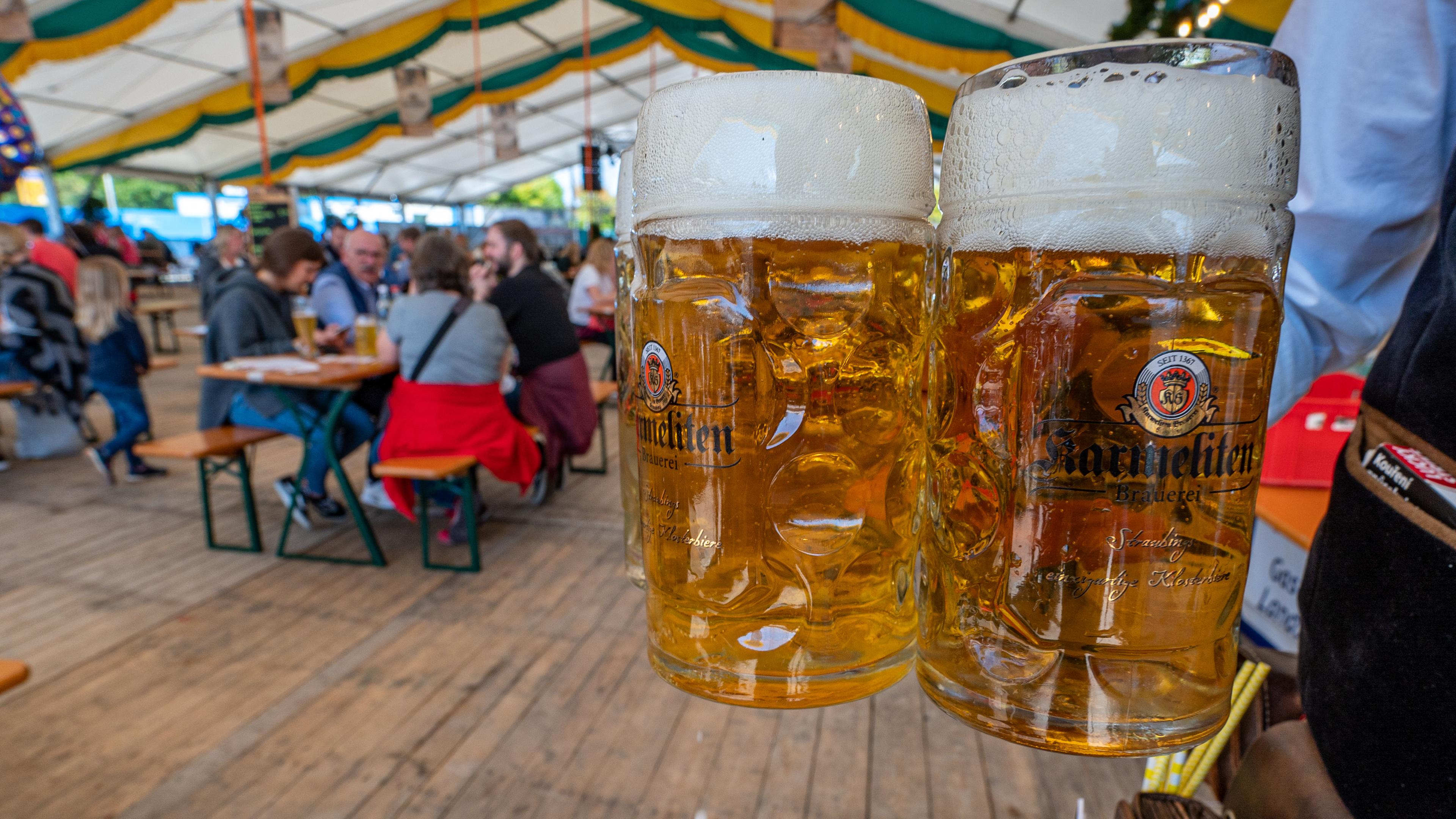 Bierkrüge werden von einem Angestellten in einem Festzelt getragen
