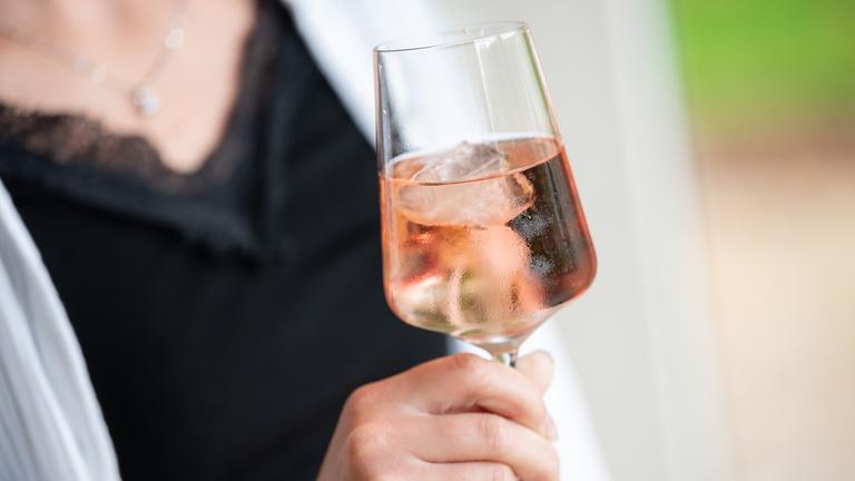 Eine Frau hat ein Weinglas in der Hand - Schwangerschaft ist auf dem Bild nicht zu sehen