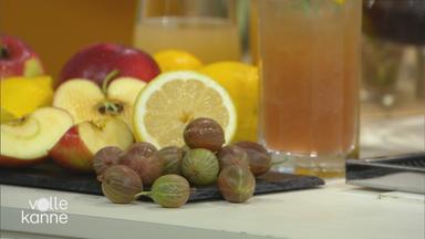 Ein alkoholfreier Bier-Cocktail im Glas und daneben Früchte, darunter Zitrone, Trauben und Apfel.