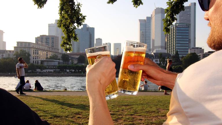 Zwei Männer stoßen in der Abendsonne mit alkoholfreiem Bier an.