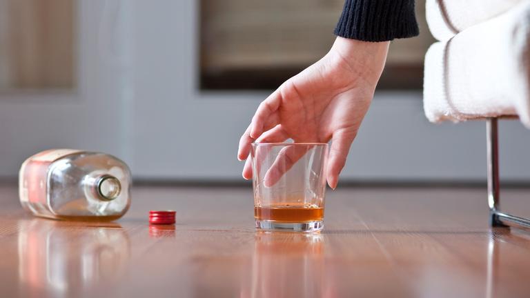 Eine Frau greift nach eine Glas mit Rum. (Symbolbild)