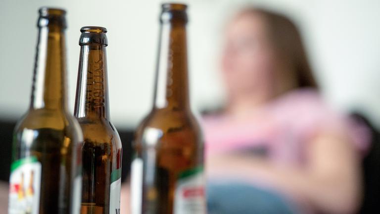 Berlin: Eine junge Frau sitzt hinter leeren Bierflaschen. 