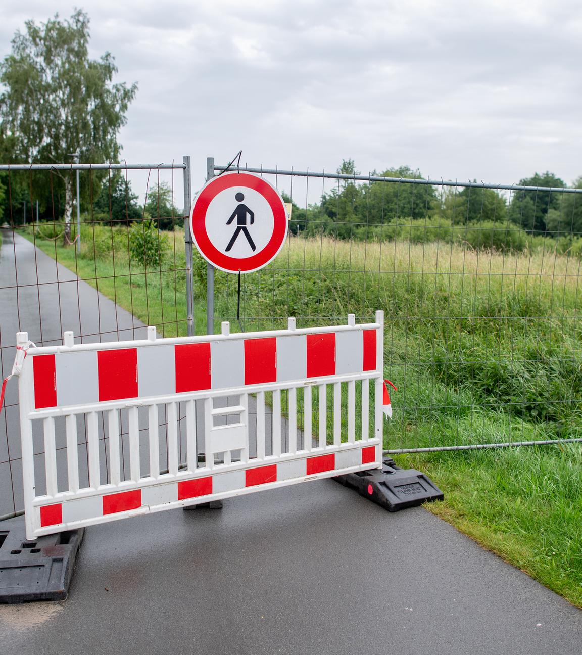Niedersachsen, Vechta: Ein Bauzaun steht an einem Weg und sperrt den Bereich um ein Regenrückhaltebecken ab.