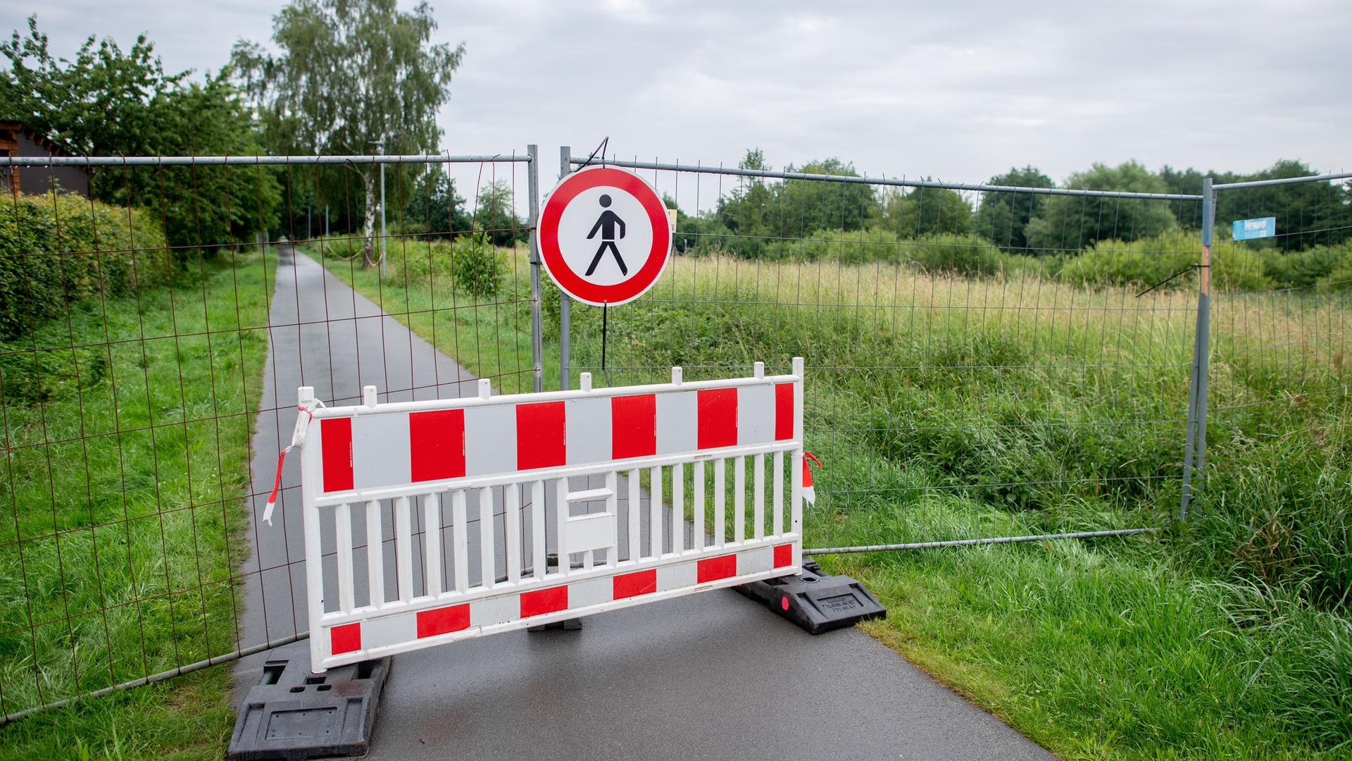 Niedersachsen, Vechta: Ein Bauzaun steht an einem Weg und sperrt den Bereich um ein Regenrückhaltebecken ab.