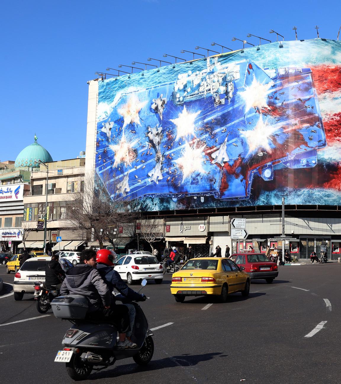 Iraner gehen am 31.01.2026 in der Nähe einer riesigen Anti-US-Plakatwand am Enqelab-Platz in Teheran, Iran, vorbei. 
