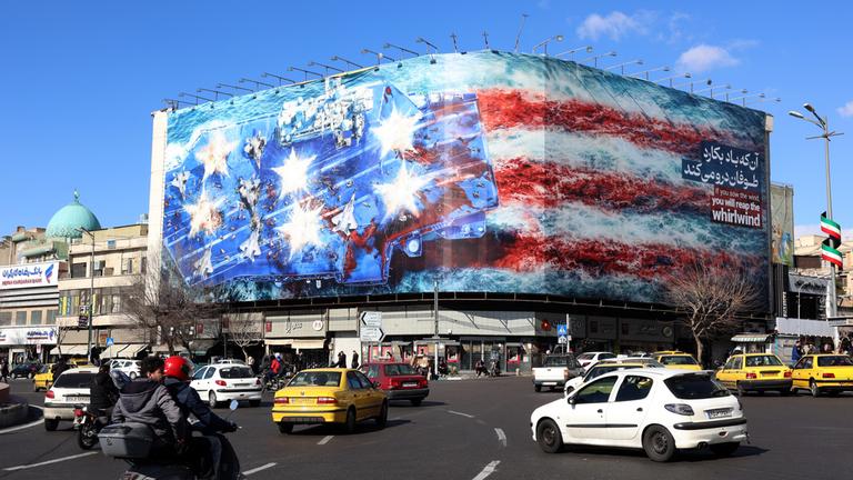 Iraner gehen am 31.01.2026 in der Nähe einer riesigen Anti-US-Plakatwand am Enqelab-Platz in Teheran, Iran, vorbei. 