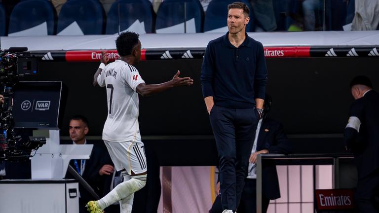 Vinicius Junior gestikuliert hinter dem Rücken von Xabi Alonso