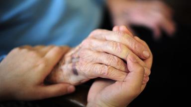 Eine Pflegekraft hält in einem Seniorenheim die Hand einer Bewohnerin, aufgenommen am 23.01.2014