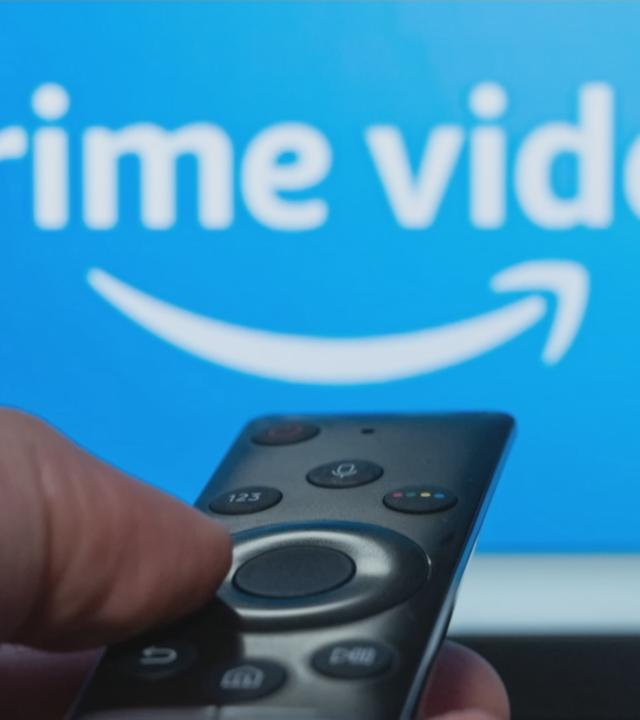 TV-Bildschirm auf dem man "prime video" geschrieben sieht und eine Fernbedienung davor