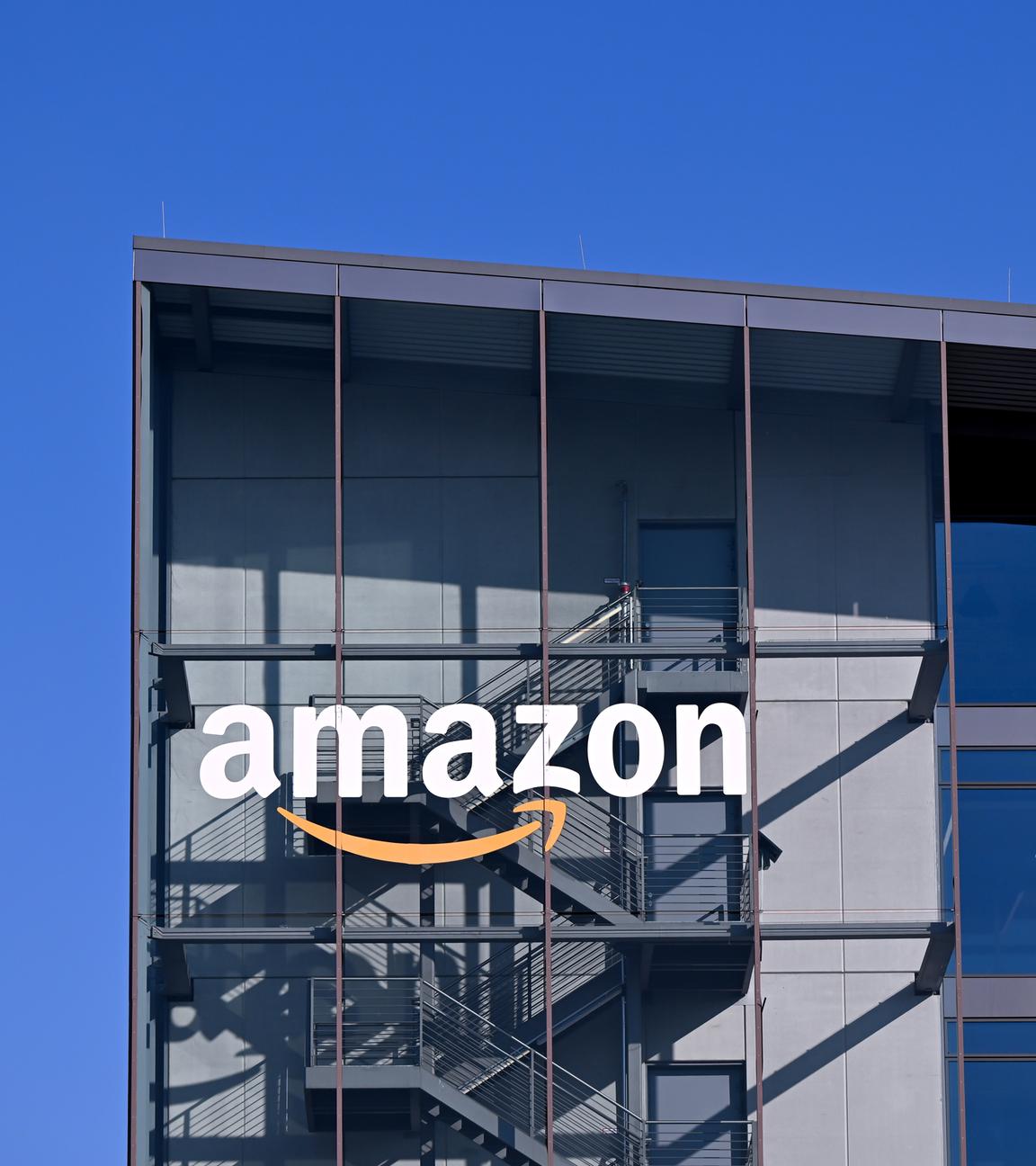 Das Logo und der Schriftzug vom Onlineversandhändler Amazon sind an der Fassade der Zentrale von Amazon Deutschland zu sehen.