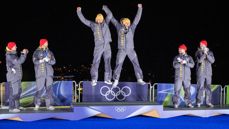 Die deutschen Bobsportler Adam Ammour, Alexander Schaller, Johannes Lochner, Georg Fleischhauer, Francesco Friedrich und Alexander Schuller jubeln bei der Siegerehrung der Olympischen Winterspiele in Cortina auf dem Podest