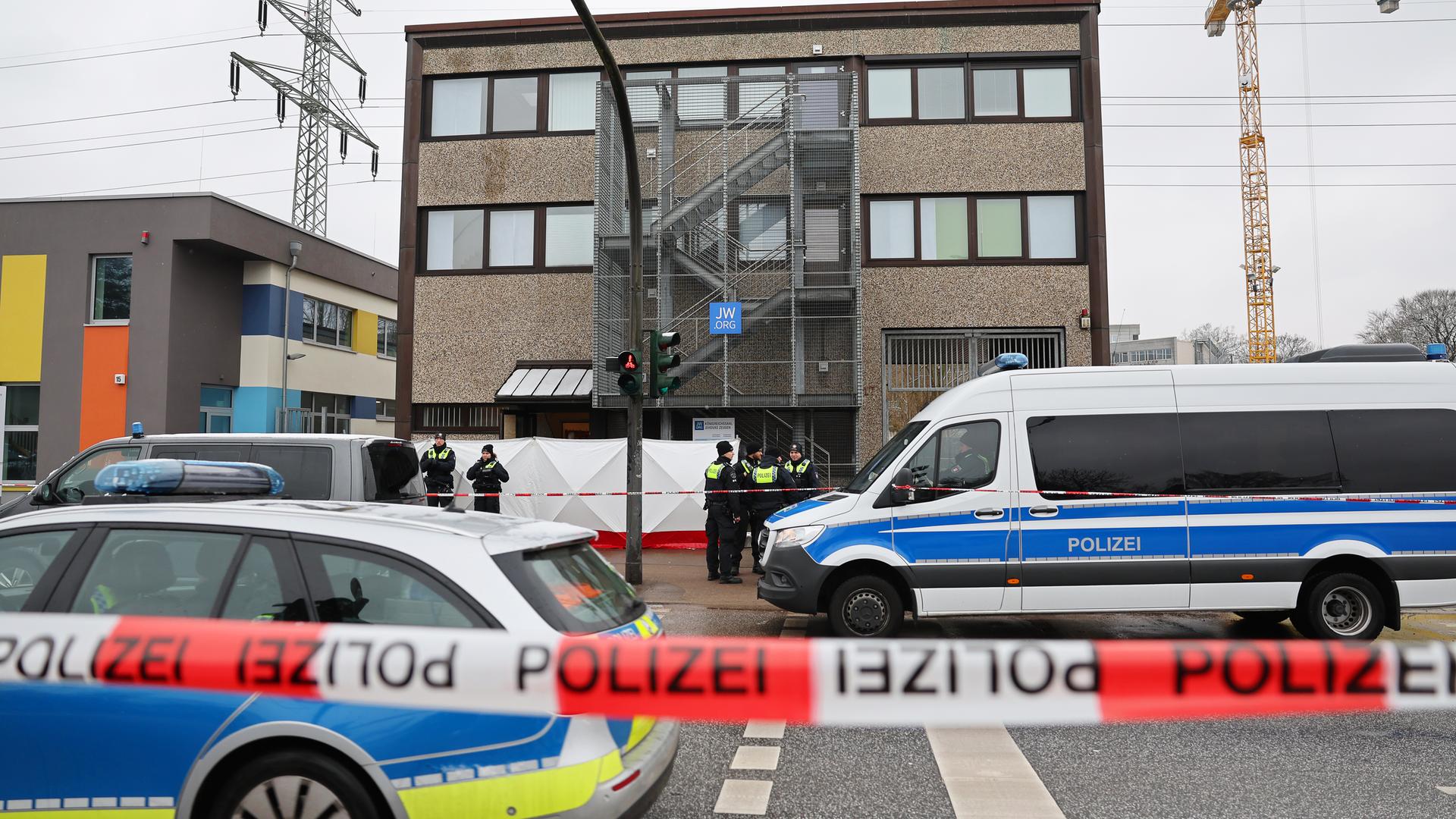 Im Mittelpunkt des Bildes ist ein Auto der Hamburger Polizei zu sehen; im Vordergrund verschwommen ein rot-weißes Absperrband.