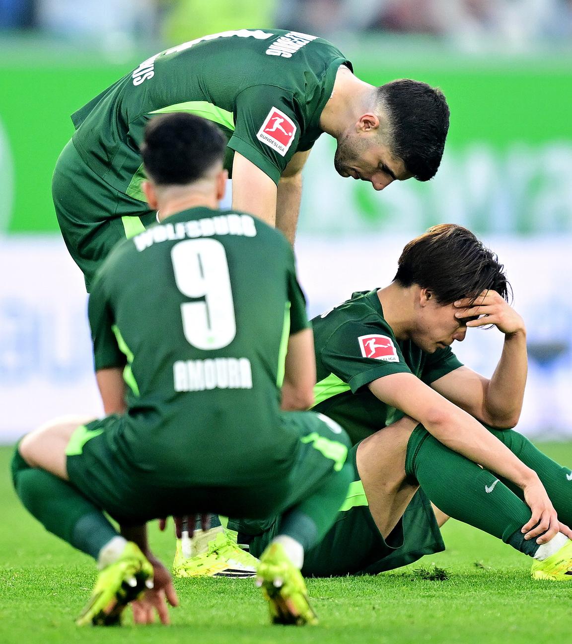 Die Wolfsburger Mohamed Amoura, Konstantinos Koulierakis und Kento Shiogai sitzen ratlos nach der Niederlage gegen den Hamburger SV am Boden