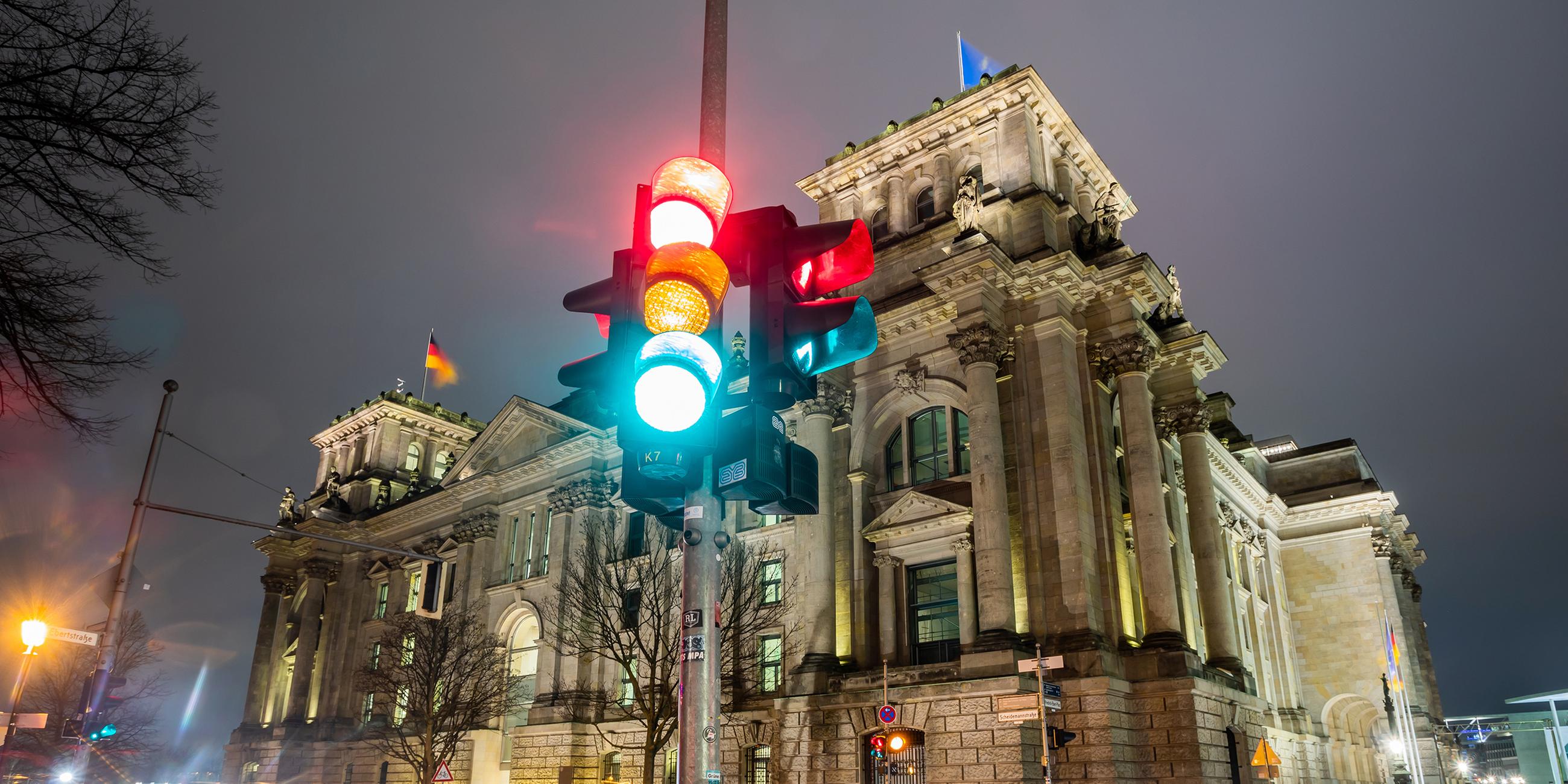 Eine Ampel leuchtet in einer Aufnahme mit Langzeitbelichtung am Morgen vor dem Reichstagsgebäude in allen drei Phasen.