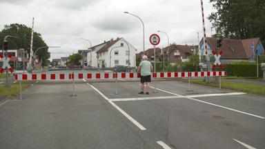 Ein Mann steht an einem gesperrten Bahnübergang.