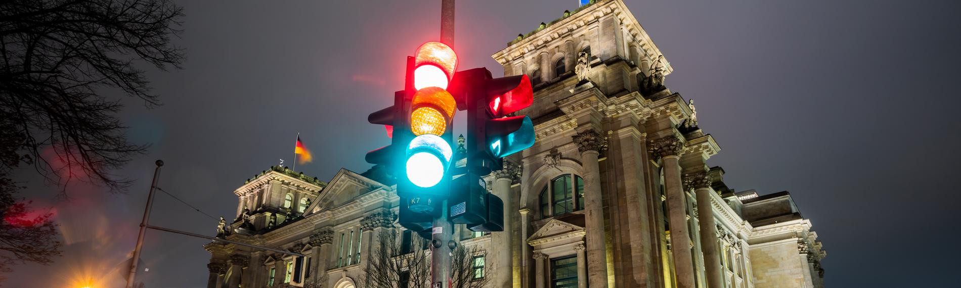 Berlin: Eine Ampel leuchtet in einer Aufnahme mit Langzeitbelichtung am Morgen vor dem Reichstagsgebäude in allen drei Phasen.