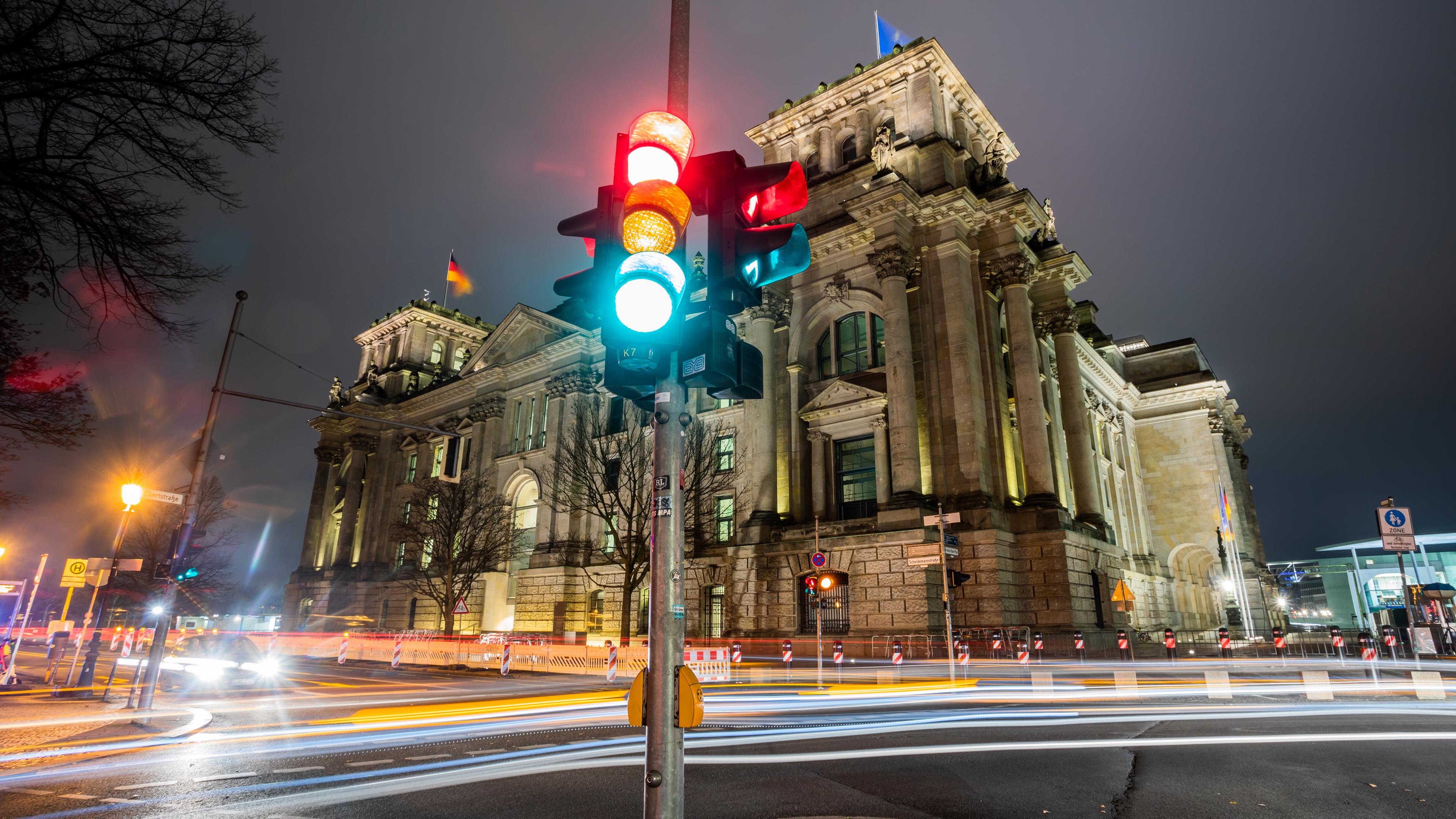 Berlin: Eine Ampel leuchtet in einer Aufnahme mit Langzeitbelichtung am Morgen vor dem Reichstagsgebäude in allen drei Phasen.