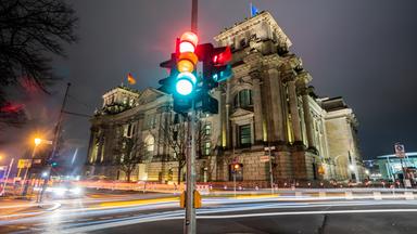 Berlin: Eine Ampel leuchtet in einer Aufnahme mit Langzeitbelichtung am Morgen vor dem Reichstagsgebäude in allen drei Phasen.