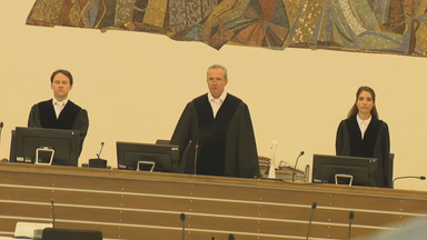 Das Bild zeigt drei Richter in einem Gerichtssaal. Das Bild ist leicht angewinkelt.